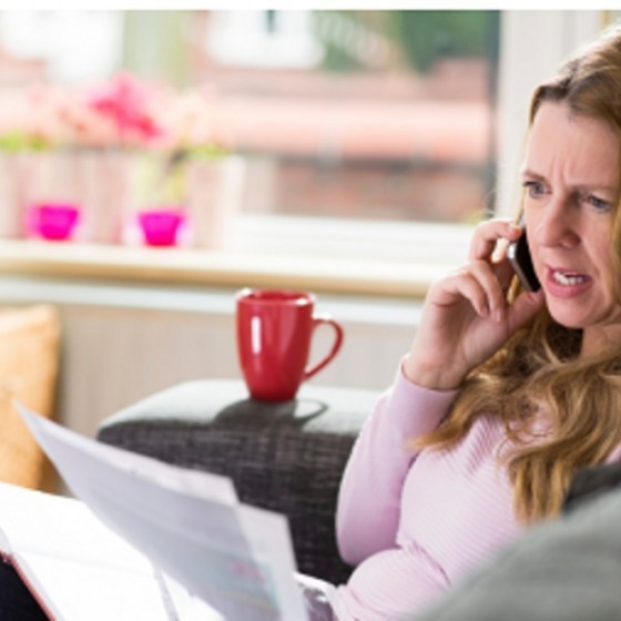 vrouw aan de telefoon met een brief in haar hand