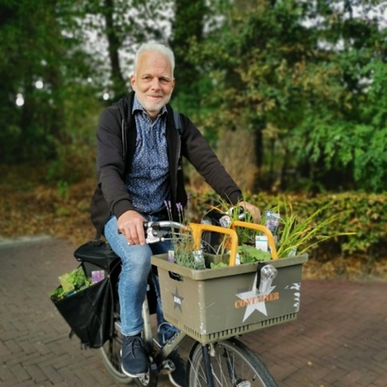 man op de fiets met een kratje met groen